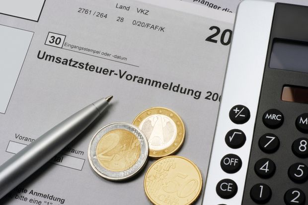 Steuervoranmeldungsformular, auf dem mehrere Euromünzen und ein Taschenrechner liegen